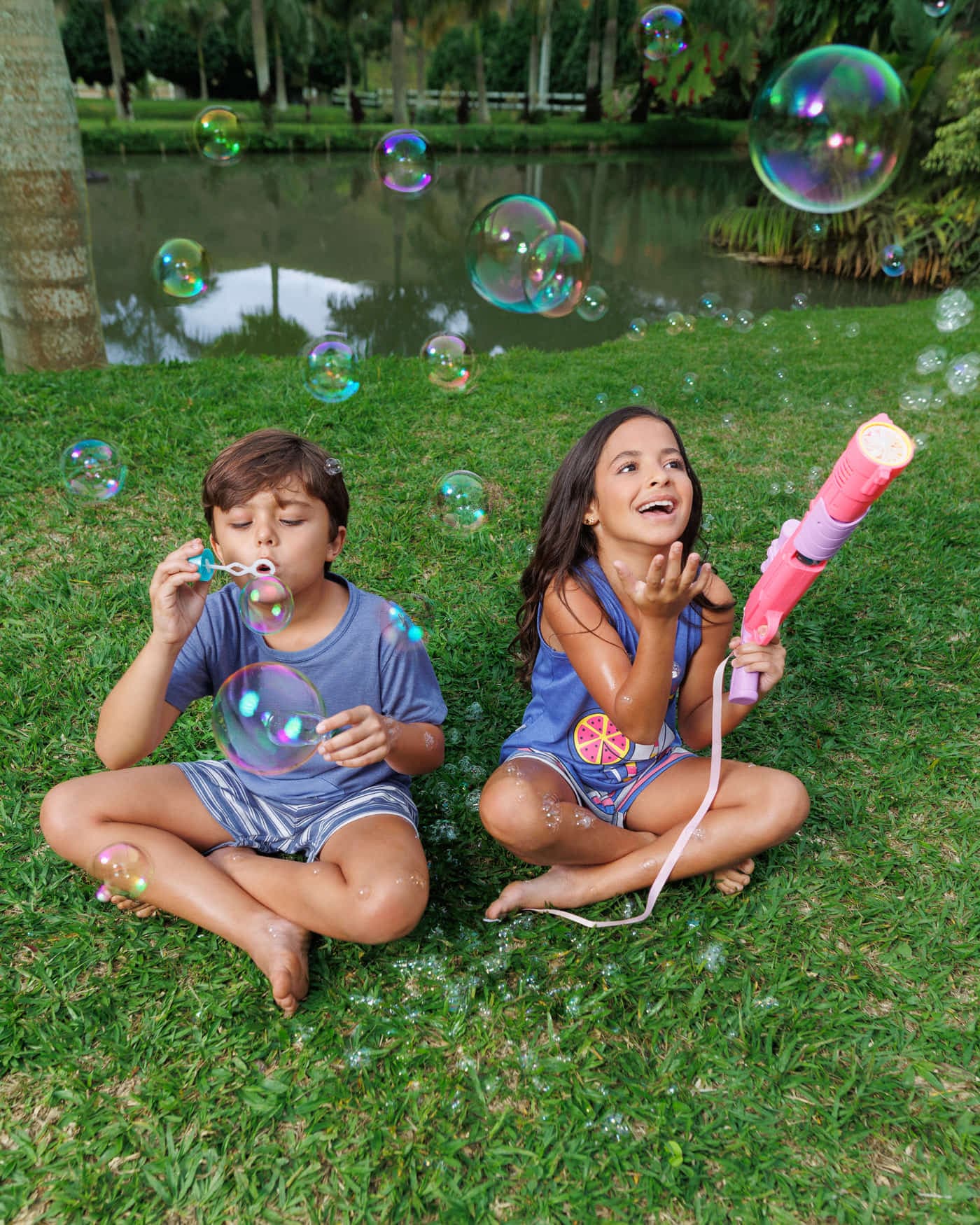 Crianças com pijama curto azul brincando com bolhas de sabão