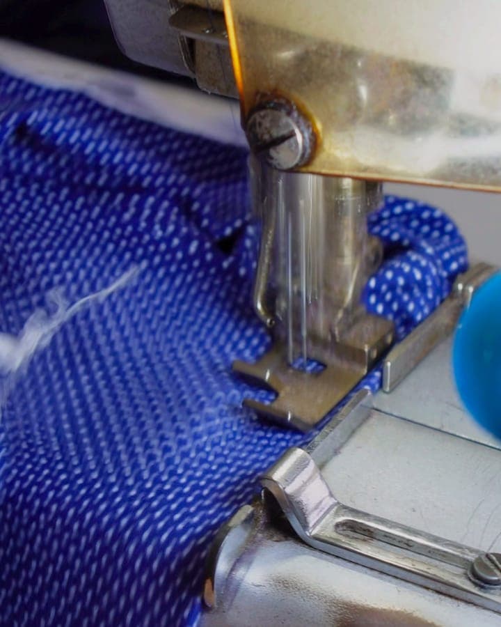 Máquina de costura fechando uma peça de tecido azul